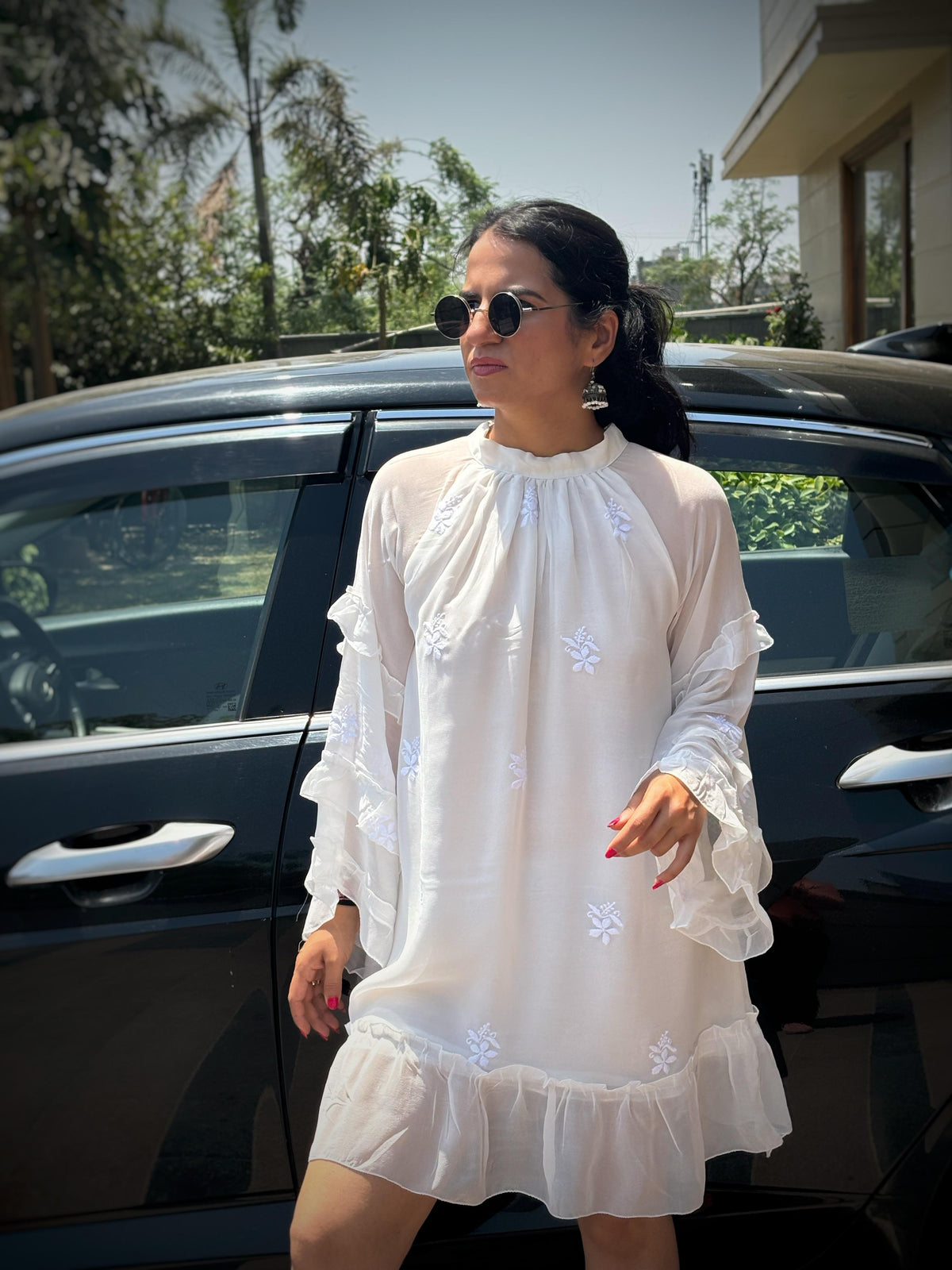 Adaa off-white Chikankari ruffle mini dress — lifestyle standing in front of car, personal occasion wear