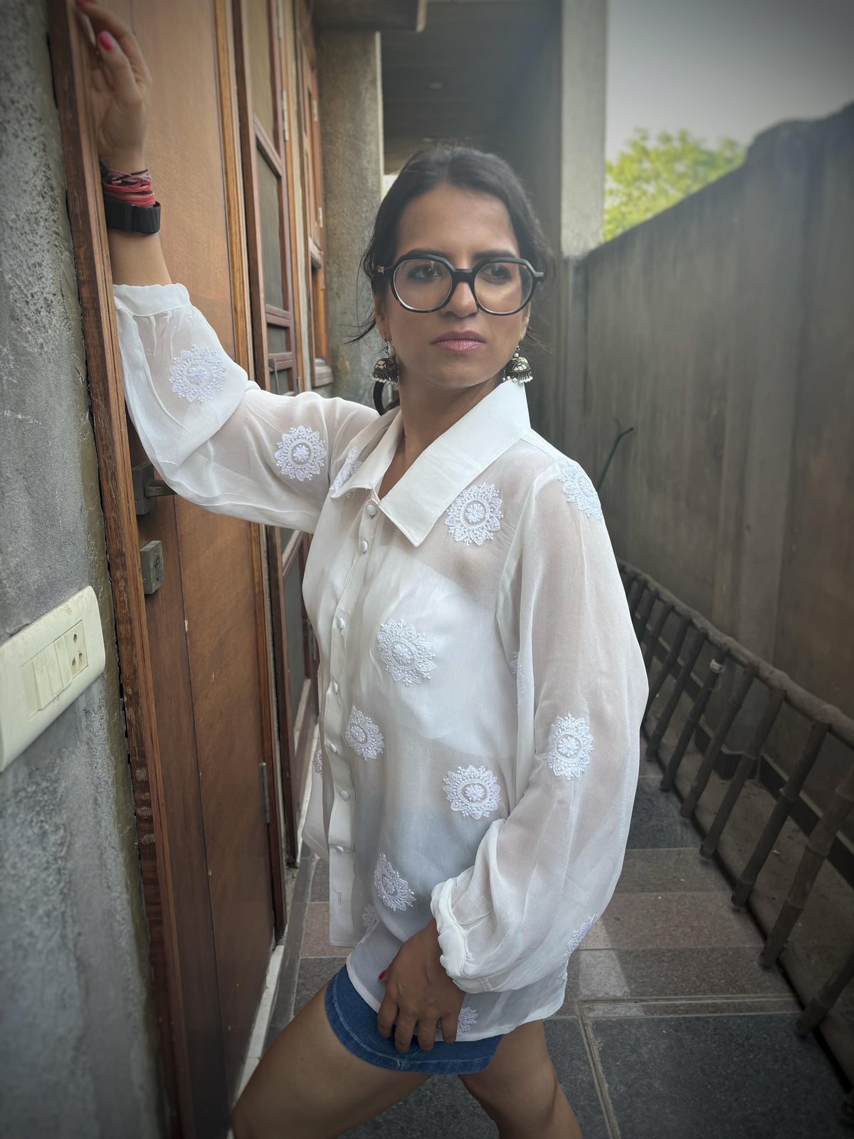 Rooh off-white Chikankari oversized shirt — left side view standing against wall, relaxed oversized silhouette